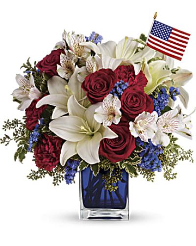 <p>A patriotic pick to send a brave veteran, decorate your Fourth of July picnic, or celebrate Memorial Day. Lush red, white and blue flowers are presented in a deep blue glass cube vase along with an American flag.<br />
Red roses, white asiatic lilies, white alstroemeria, blue statice and red carnations are gathered with green pitta negra, seeded eucalyptus and a small American flag in a cobalt blue glass cube.</p>